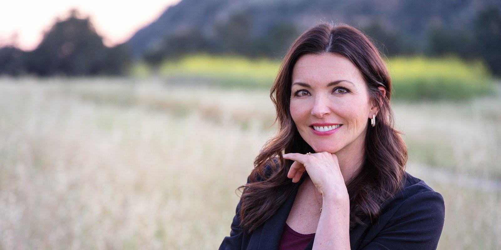 Janie Hart, LMFT, smiling outdoors in a field at golden hour