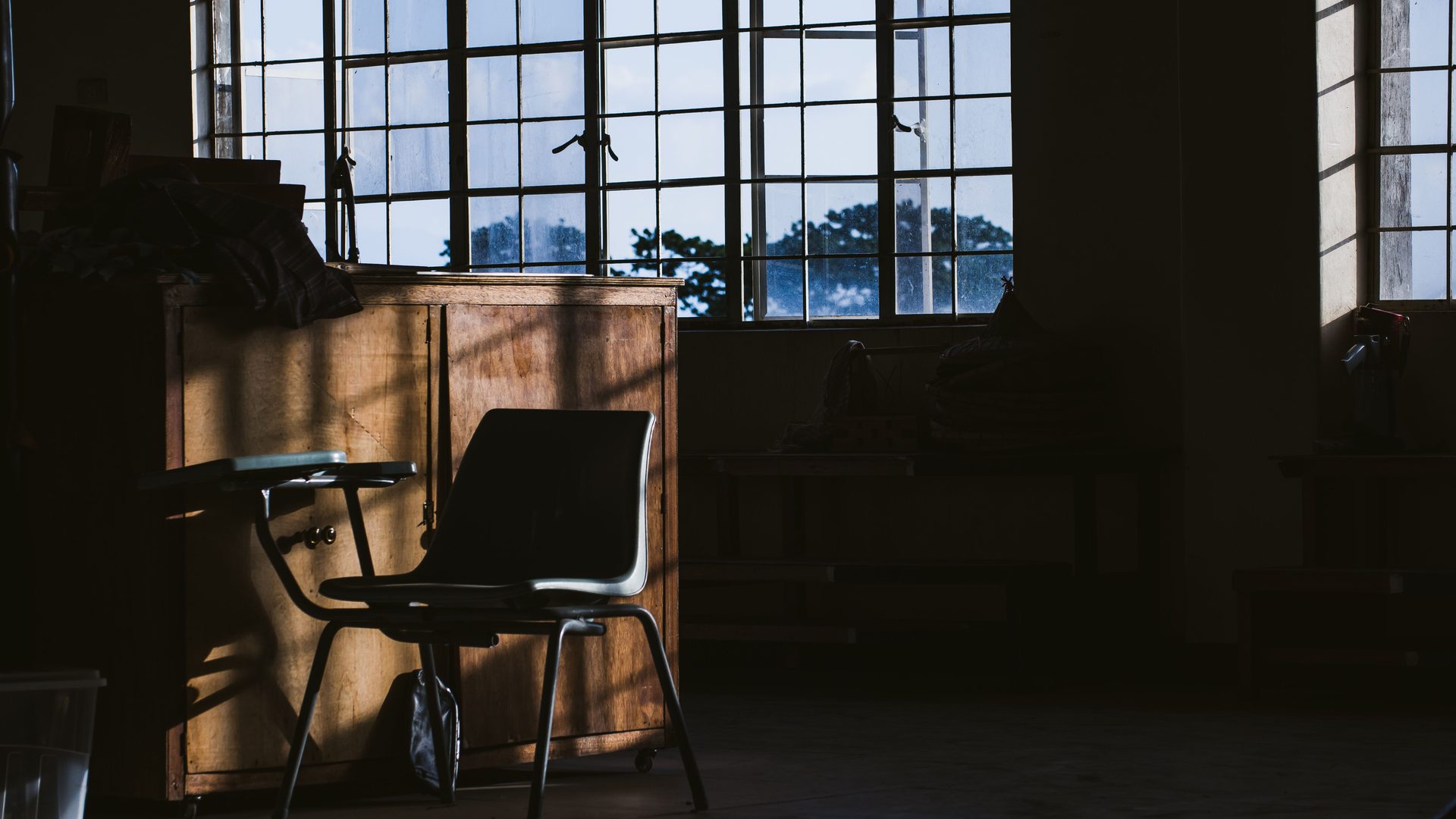 A quiet room with a chair and tall windows in low daylight